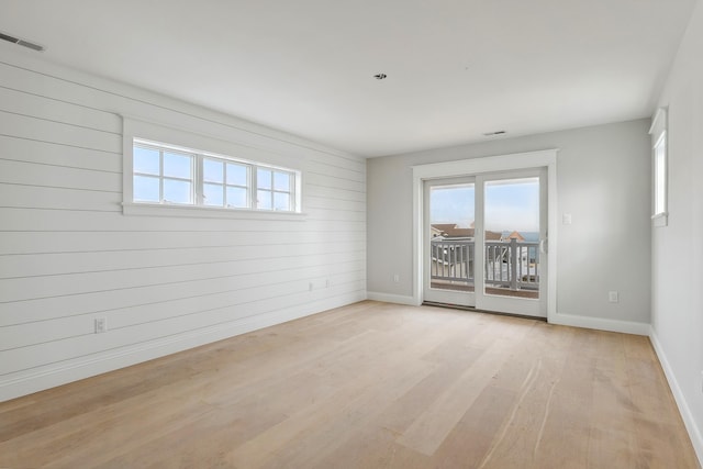 empty room featuring wooden walls and light wood-type flooring