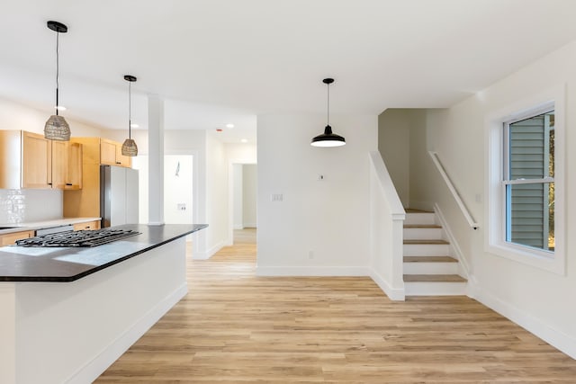 kitchen with light brown cabinets, light hardwood / wood-style floors, stainless steel refrigerator, and pendant lighting