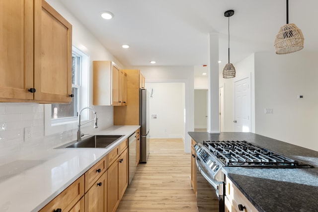 kitchen featuring sink, hanging light fixtures, tasteful backsplash, light hardwood / wood-style flooring, and appliances with stainless steel finishes