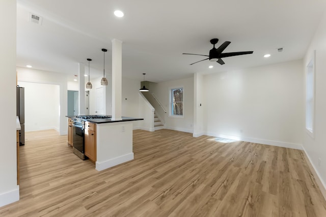 kitchen featuring ceiling fan, a center island, stainless steel appliances, decorative light fixtures, and light wood-type flooring