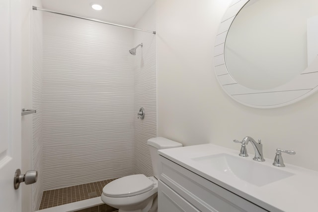 bathroom featuring tiled shower, vanity, and toilet