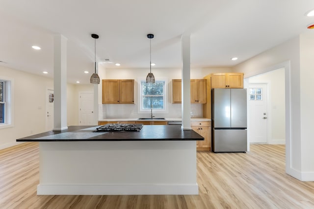 kitchen with sink, stainless steel appliances, pendant lighting, light hardwood / wood-style floors, and decorative backsplash