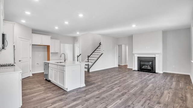 kitchen featuring white cabinetry, a kitchen island with sink, sink, and light wood-type flooring