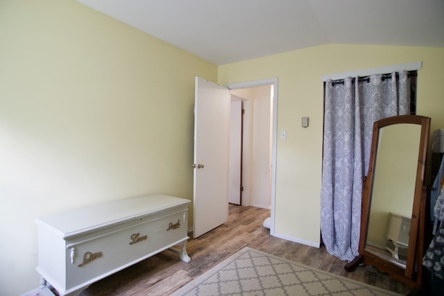 unfurnished bedroom with hardwood / wood-style flooring and lofted ceiling