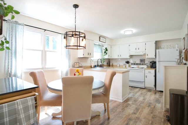 kitchen featuring light wood-type flooring, white appliances, sink, decorative light fixtures, and white cabinetry