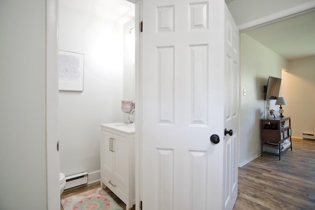 bathroom with hardwood / wood-style flooring, toilet, vanity, and a baseboard heating unit