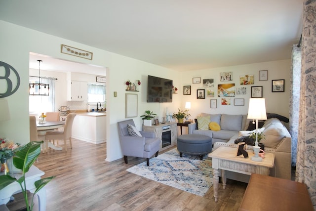 living room with light wood-type flooring, sink, and an inviting chandelier