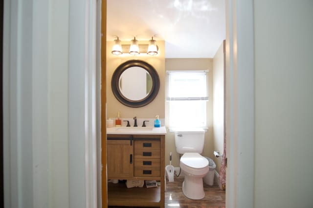 bathroom with toilet, vanity, and hardwood / wood-style flooring