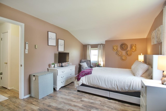 bedroom with vaulted ceiling and light wood-type flooring