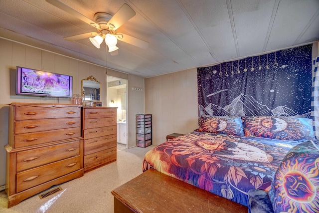 bedroom with ceiling fan, visible vents, carpet floors, and ensuite bath