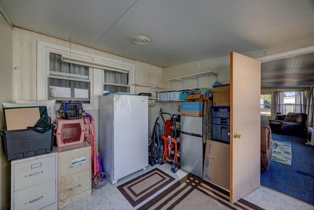 interior space with concrete flooring and freestanding refrigerator