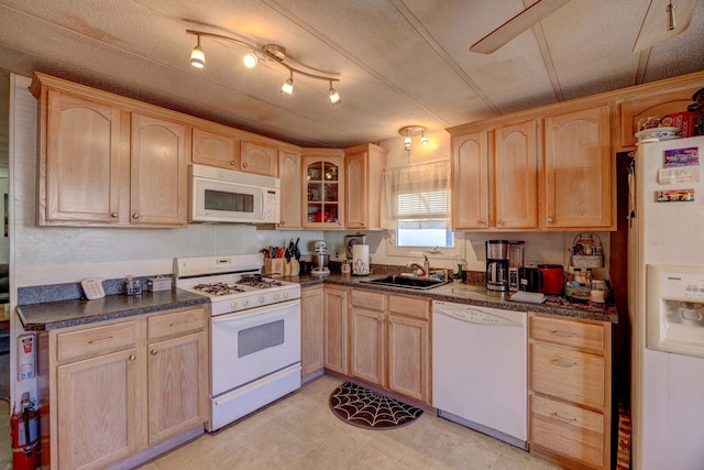 kitchen featuring light brown cabinets, white appliances, and dark countertops