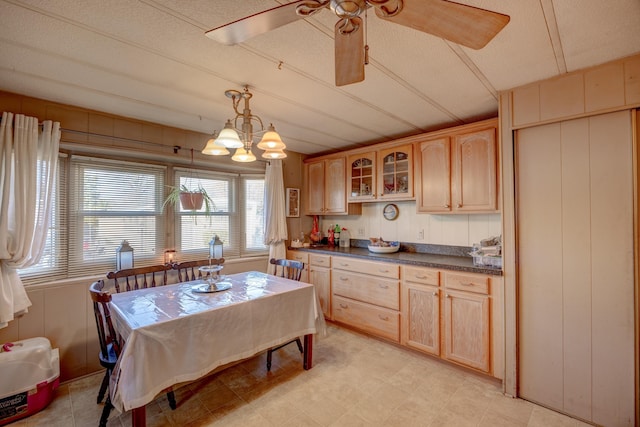 kitchen featuring a ceiling fan, dark countertops, glass insert cabinets, and light brown cabinetry