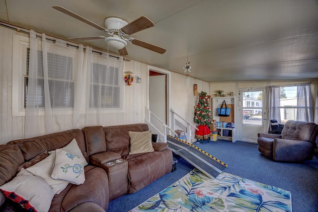 living area featuring stairs, carpet flooring, and a ceiling fan