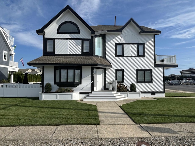 view of front of property featuring a front yard and a balcony