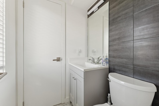 bathroom featuring vanity, toilet, and tile walls