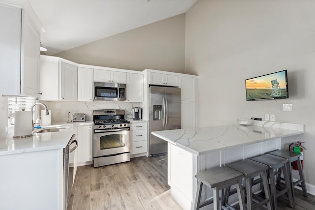 kitchen with white cabinets, sink, kitchen peninsula, and stainless steel appliances