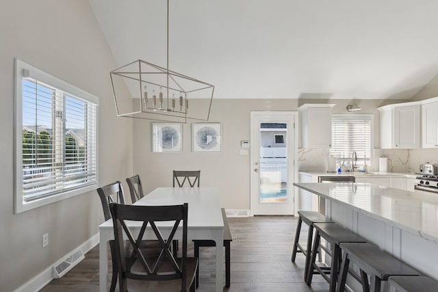 dining area with plenty of natural light, lofted ceiling, and dark wood-type flooring