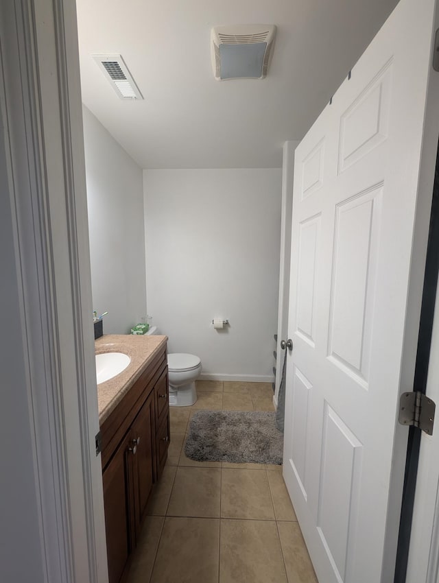 half bath with tile patterned flooring, visible vents, toilet, vanity, and baseboards