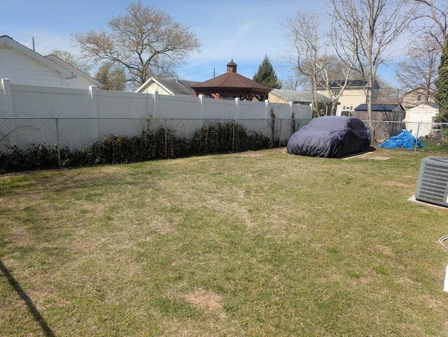 view of yard featuring fence, a storage unit, an outdoor structure, and central AC