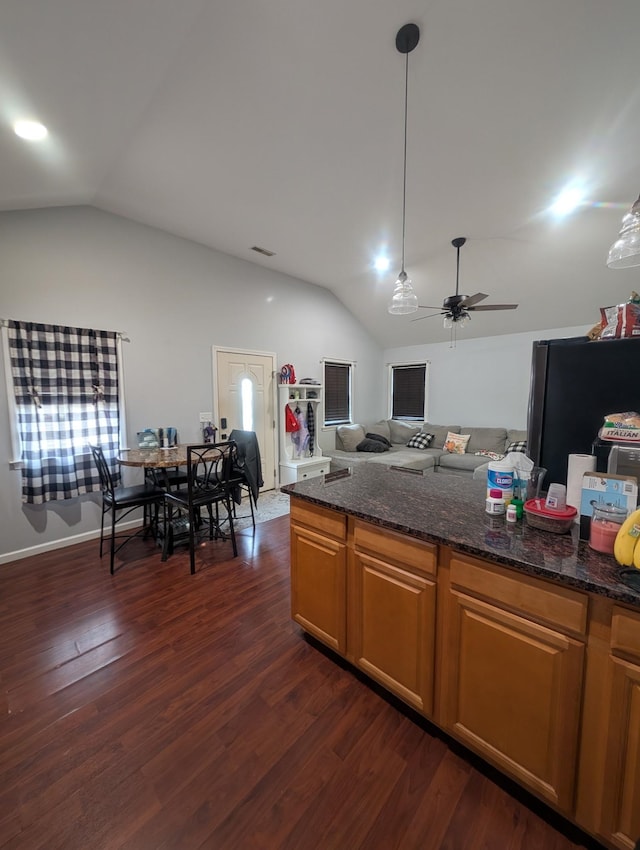 kitchen featuring dark stone counters, dark wood finished floors, vaulted ceiling, freestanding refrigerator, and a ceiling fan