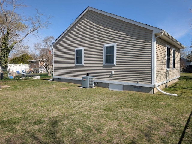 view of property exterior with a lawn, central AC, and fence