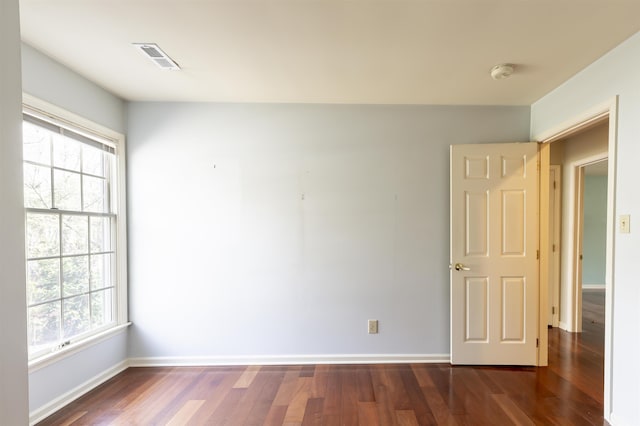 spare room featuring visible vents, baseboards, dark wood-style floors, and a healthy amount of sunlight