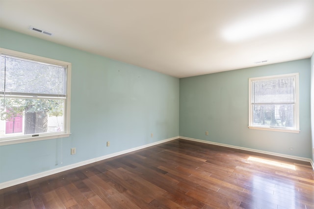 spare room with plenty of natural light, visible vents, and wood finished floors