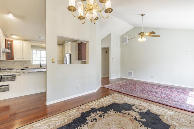 interior space with dark wood finished floors, vaulted ceiling, visible vents, and ceiling fan with notable chandelier