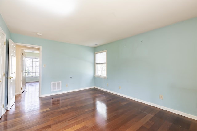 unfurnished room with baseboards, hardwood / wood-style flooring, and visible vents