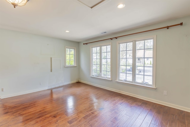 unfurnished room featuring baseboards, hardwood / wood-style floors, visible vents, and recessed lighting