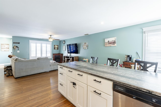 kitchen with open floor plan, ceiling fan, white cabinetry, light wood finished floors, and dishwasher