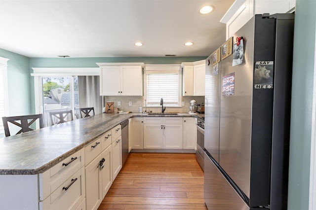kitchen featuring a sink, appliances with stainless steel finishes, a peninsula, and a healthy amount of sunlight