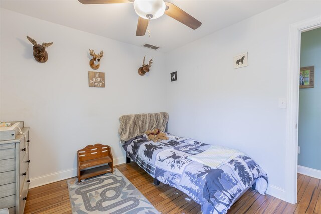 bedroom with wood-type flooring, a ceiling fan, baseboards, and visible vents