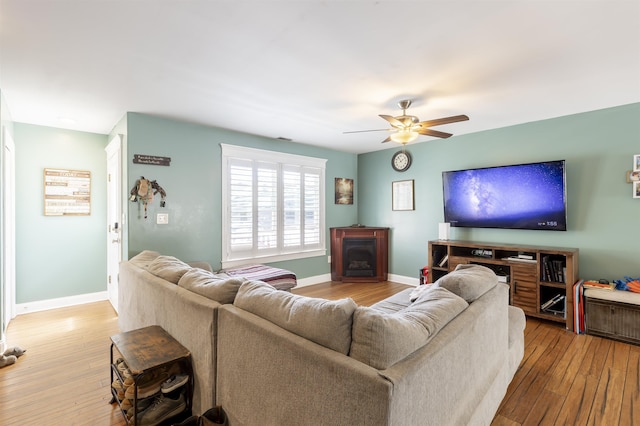 living room featuring wood-type flooring, baseboards, and ceiling fan