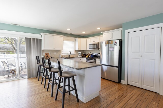 kitchen with stainless steel appliances, a kitchen breakfast bar, a sink, and light wood-style flooring