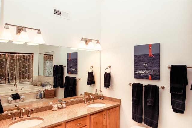 bathroom with double vanity, a garden tub, visible vents, and a sink