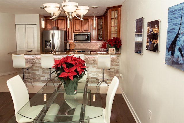 dining space featuring baseboards, a chandelier, and wood finished floors