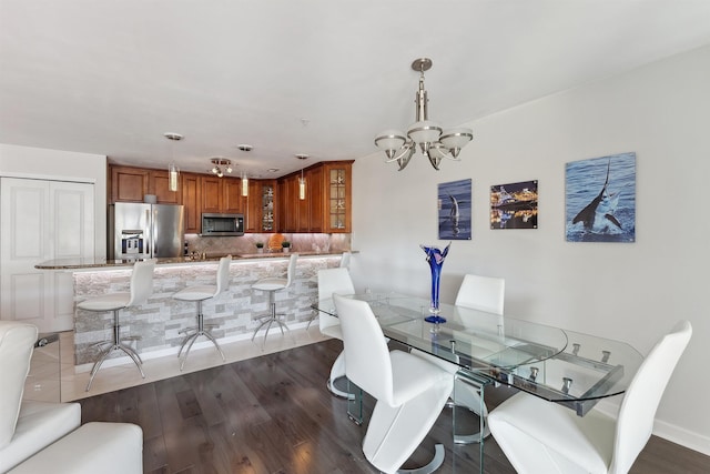 dining area with dark wood finished floors and an inviting chandelier