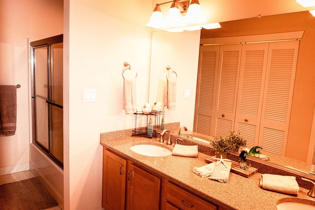 bathroom with bath / shower combo with glass door, a closet, and vanity