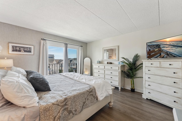 bedroom with access to exterior, dark wood-style floors, baseboards, and a textured ceiling