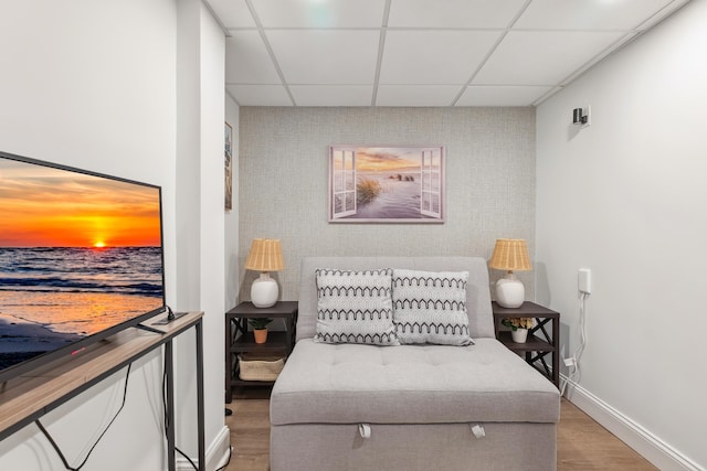 bedroom featuring light wood-style floors, a drop ceiling, baseboards, and an accent wall