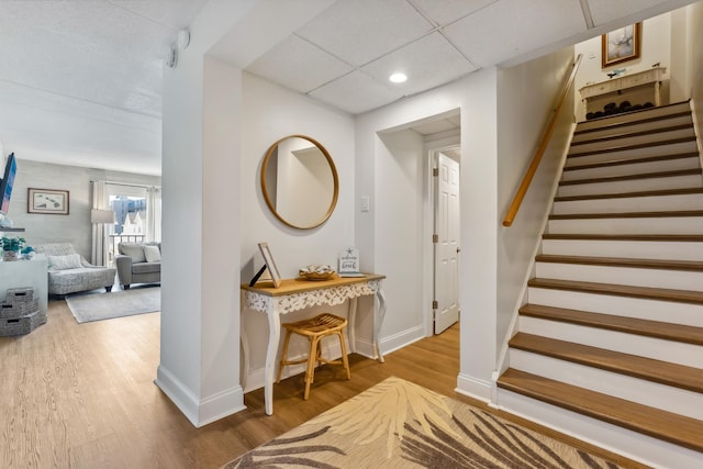 foyer featuring wood finished floors, baseboards, stairs, and recessed lighting