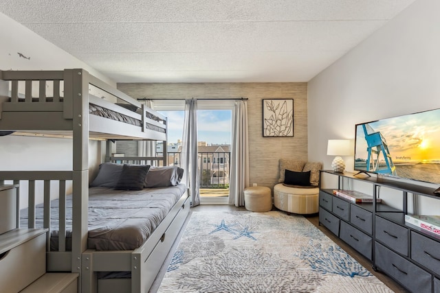bedroom featuring wood finished floors, access to outside, and a textured ceiling