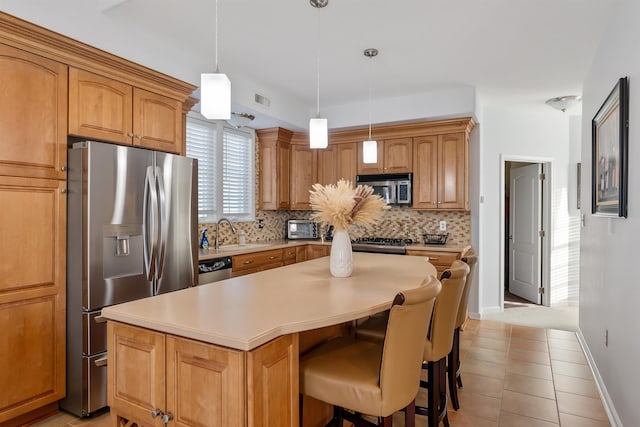 kitchen featuring a center island, hanging light fixtures, stainless steel appliances, backsplash, and light tile patterned flooring