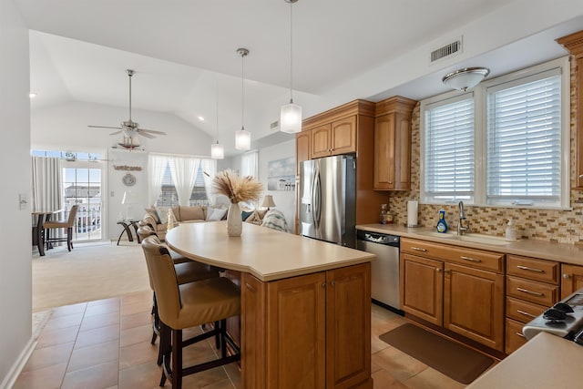 kitchen with ceiling fan, sink, stainless steel appliances, tasteful backsplash, and a kitchen island