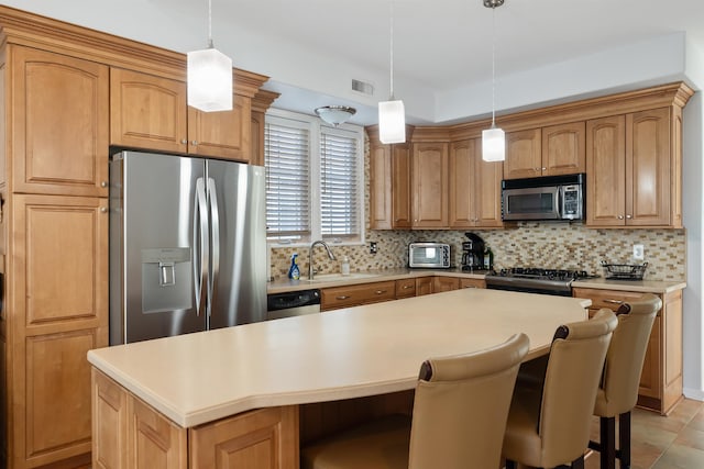 kitchen featuring sink, hanging light fixtures, backsplash, a kitchen island, and appliances with stainless steel finishes