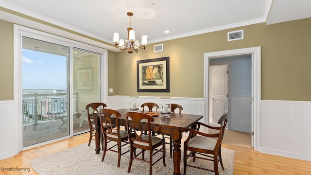 dining area featuring light wood-style floors, wainscoting, and visible vents