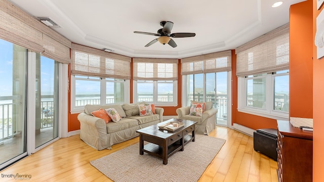 sunroom / solarium featuring plenty of natural light, visible vents, ceiling fan, and a raised ceiling