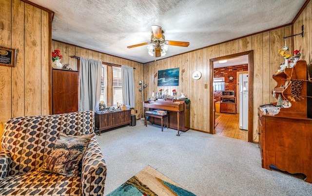 living area featuring ceiling fan, light colored carpet, a textured ceiling, and wood walls